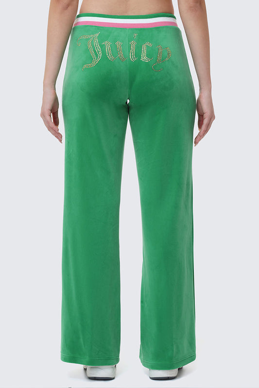 Someone stands with their back to the camera, wearing Heritage Stripe Bling Velour Track Pants featuring a rhinestone Juicy logo on the back and a sporty striped waistband.