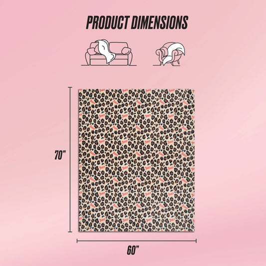 The Plush Oversized Throw Blanket, shown on a pink background, features a leopard and heart print. Measuring 70 x 60 inches, it's perfect for use on a sofa or as a cozy wrap, offering both style and comfort.