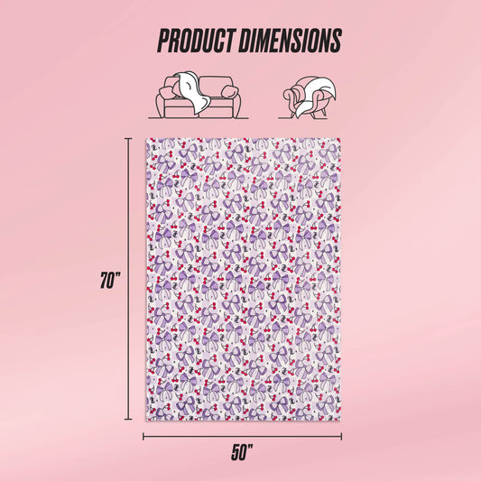 The Kids Plush Throw Blanket by Juicy Couture Kids features a colorful heart and paw print design, measures 70 x 50 inches, and is shown draped on a sofa and wrapped around a person. The ultra-soft material is ideal for cozy moments. Product Dimensions shown.