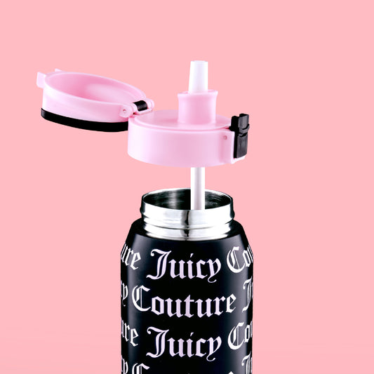 The Glam Getaway Hydration Stainless Steel Tumbler by Juicy Couture, featuring a black body, white gothic logo, pink flip-top lid, and white straw, is displayed against a solid pink background.
