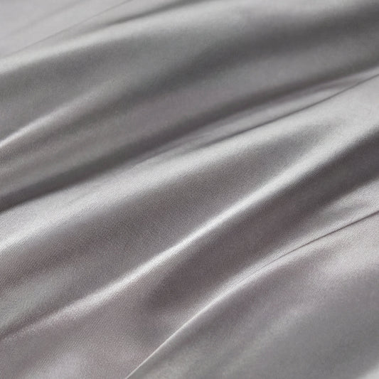 Smooth, shiny silver-gray fabric with gentle folds and soft reflections highlights the silky texture of the Solid Satin Sheet Set—perfect for adding a touch of ultra-soft luxury to your bedroom.