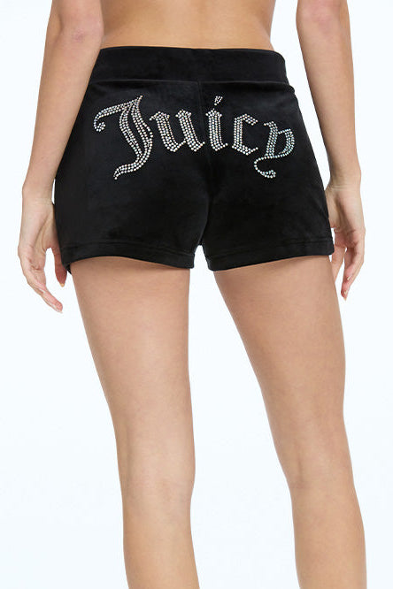 A person wears Big Bling Velour Track Shorts in black, featuring side pockets and “Juicy” in rhinestones across the back. The photo shows a rear view from waist to mid-thigh.