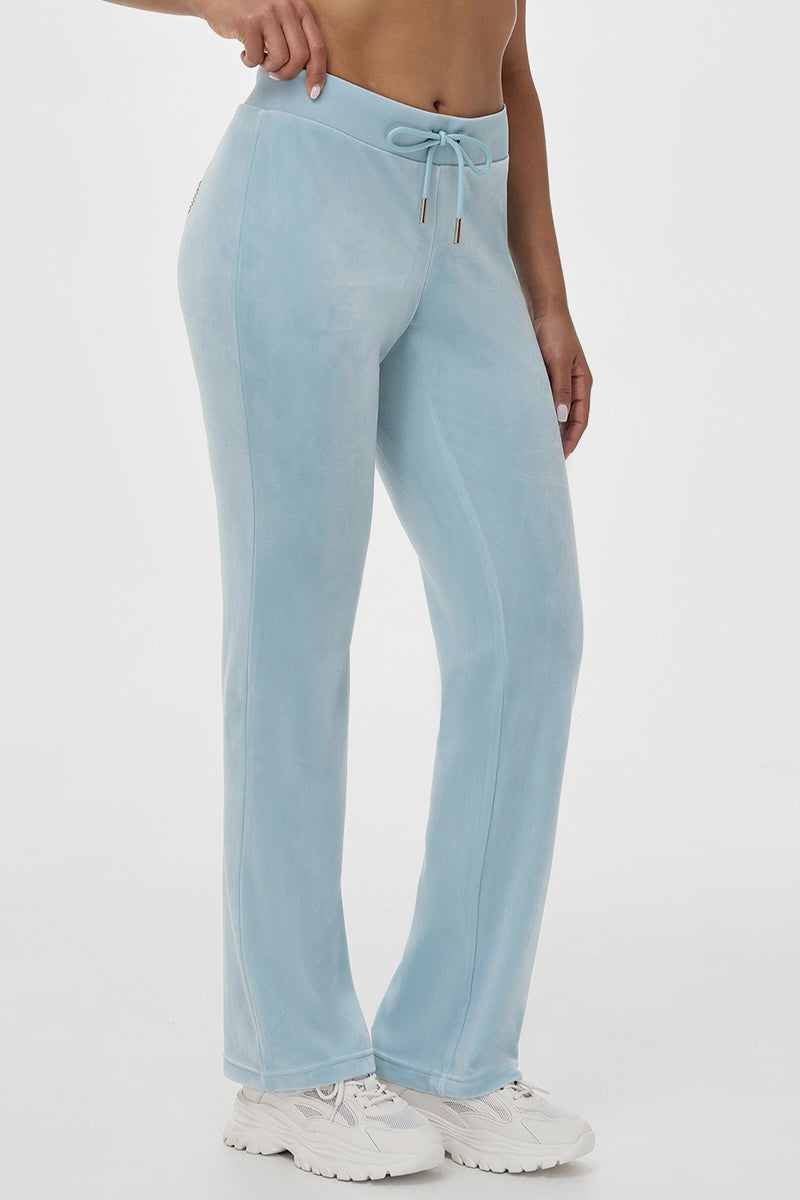 Wearing light blue high-waisted jogger pants with a drawstring, the person pairs them with the Heart & Arrow Baby Tee and white chunky sneakers, standing against a plain white background.
