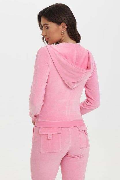 A woman with dark hair faces slightly away, showcasing the back of her light pink French Terry Embroidered Shorts against a plain white background.