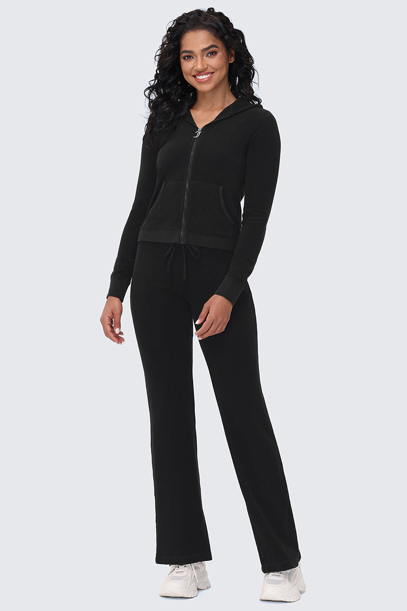 A woman smiles in the Big Bling Washed Terry Hoodie and matching black drawstring pants, paired with white sneakers, against a plain light gray background.