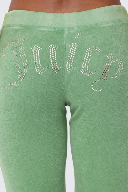 Close-up of a person wearing Big Bling Washed Terry Track Pants featuring a green terry fabric and a rhinestone “Juicy” logo across the back.