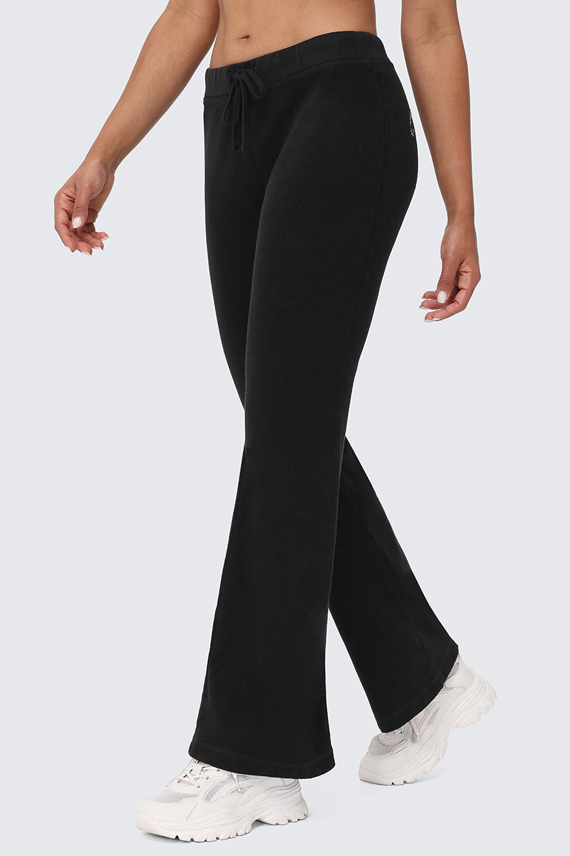 Someone in Big Bling Washed Terry Track Pants and white sneakers walks with relaxed arms against a plain light background.