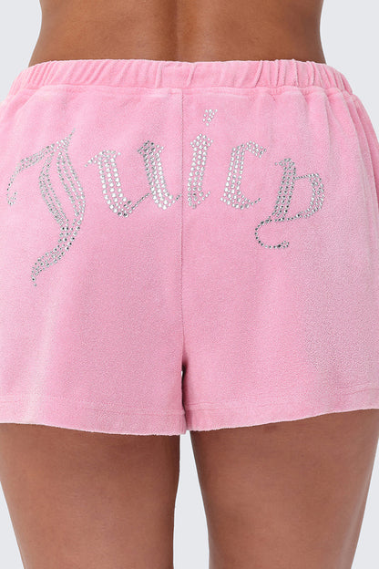 Someone wears Big Bling Washed Terry Shorts, featuring a pink towel terry fabric, drawstring waistband, and a sparkling rhinestone "Juicy" logo across the back.