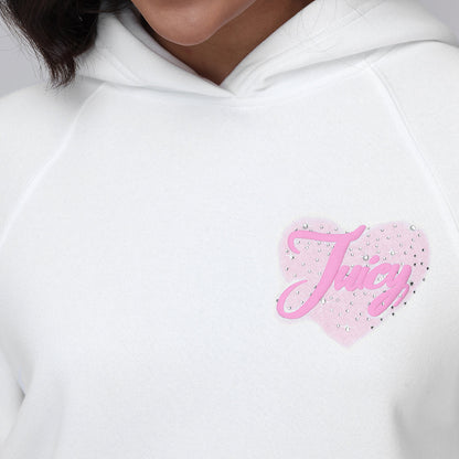 Someone wears the Sweetheart Fleece Oversized Hoodie—an oversized white fleece with a pink heart patch on the chest, “Juicy” in cursive and rhinestones. Their face is partly visible, enhancing the laid-back, casual vibe.