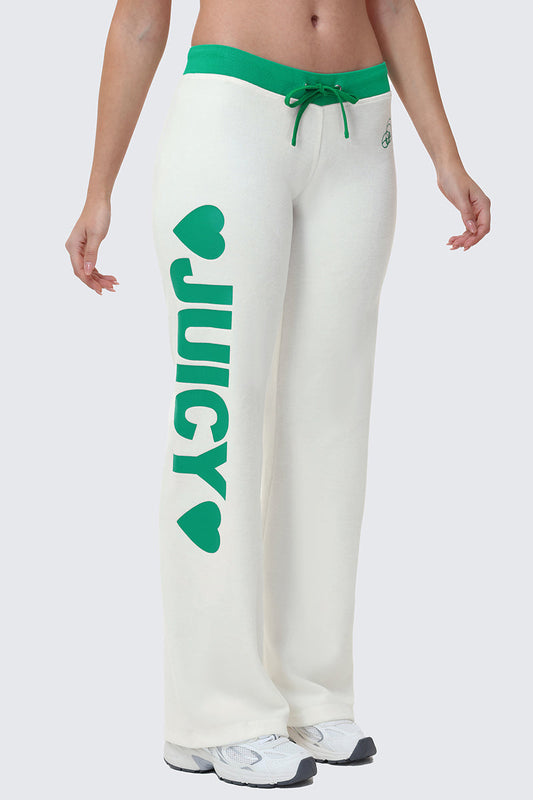 A person wears Contrast Low Rise Track Pants—white with a green waistband, drawstring, "JUICY" and green hearts on the left leg—styled with white sneakers for a sporty loungewear vibe.