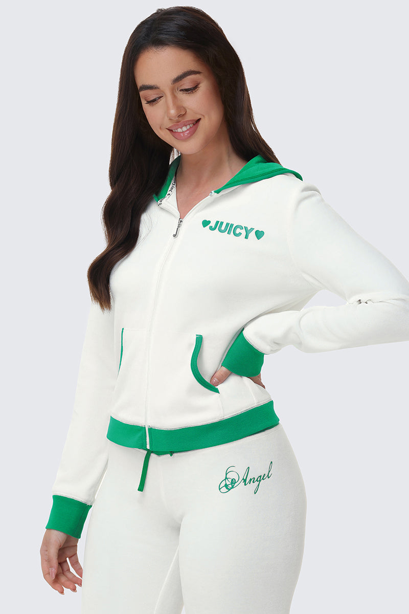 A woman in a white Contrast Trim Logo Hoodie with green trim and "Angel" pants stands smiling with one hand on her hip against a light gray background—showcasing the perfect everyday layer for sporty style.
