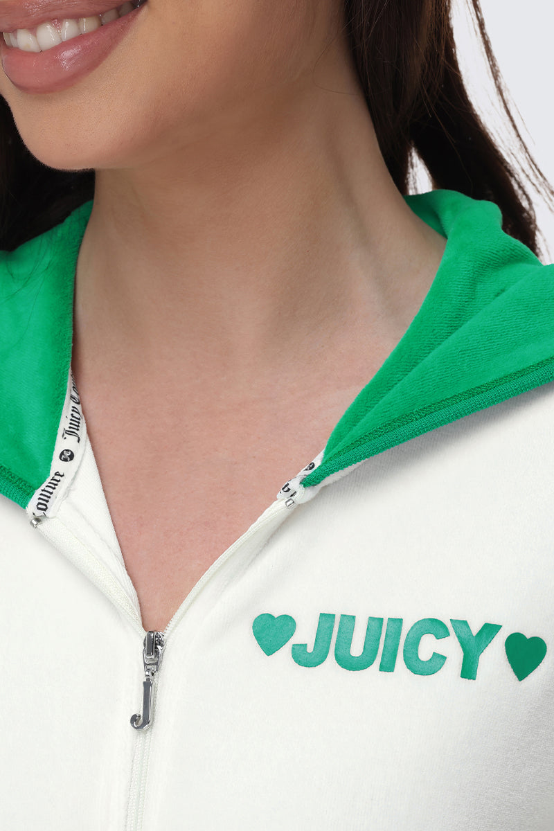 Close-up of a woman smiling, wearing a white Contrast Trim Logo Hoodie with a green hood. Only her lower face is visible. "JUICY" with green hearts decorates the left chest—a stylish, sporty layer for everyday wear.
