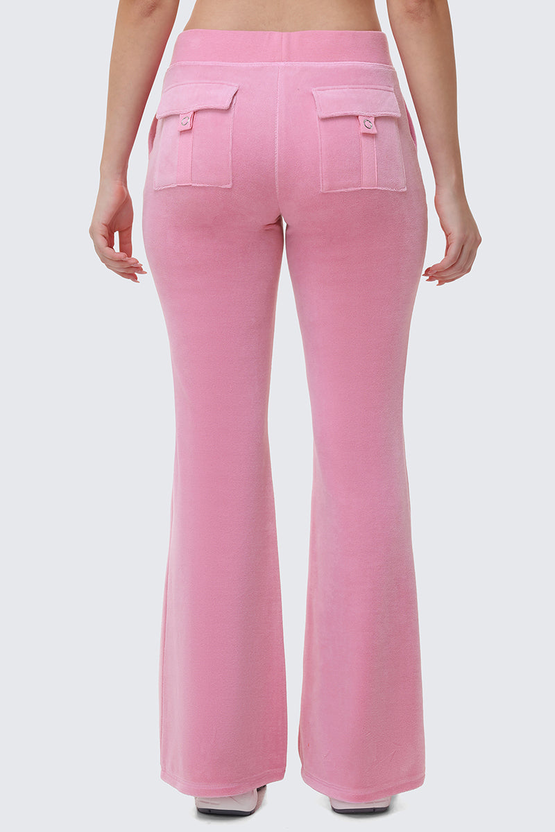 A person is seen from the back wearing Heritage Cotton Velour Track Pants in light pink, featuring a high waist, flared legs, and two flap pockets, with their arms relaxed at their sides against a plain light gray background.
