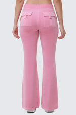 A person is seen from the back wearing Heritage Cotton Velour Track Pants in light pink, featuring a high waist, flared legs, and two flap pockets, with their arms relaxed at their sides against a plain light gray background.