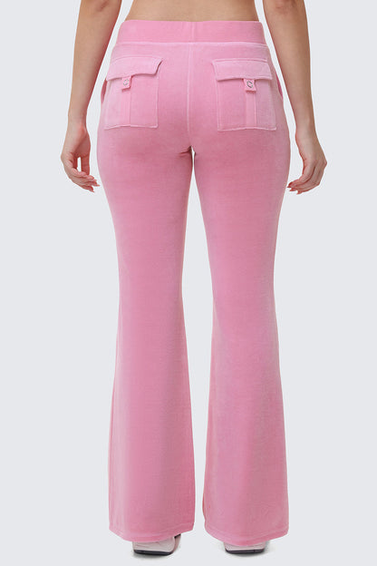 A person is seen from the back wearing Heritage Cotton Velour Track Pants in light pink, featuring a high waist, flared legs, and two flap pockets, with their arms relaxed at their sides against a plain light gray background.