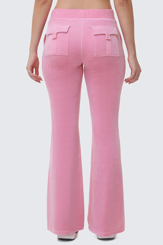 A person is seen from the back wearing Heritage Cotton Velour Track Pants in light pink, featuring a high waist, flared legs, and two flap pockets, with their arms relaxed at their sides against a plain light gray background.