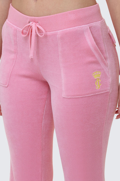 A close-up of a person wearing Heritage Cotton Velour Track Pants featuring a drawstring waist, front pockets, and a small yellow crown with initials logo on the left pocket.