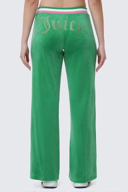 Someone stands with their back to the camera, wearing Heritage Stripe Bling Velour Track Pants featuring a rhinestone Juicy logo on the back and a sporty striped waistband.