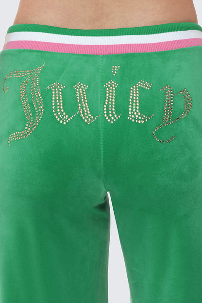 A close-up of the Heritage Stripe Bling Velour Track Pants shows wide-leg green velour with a rhinestone Juicy logo on the seat and a pink-and-white striped waistband at the top.