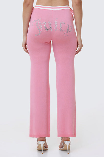 Someone is seen from behind wearing Big Bling Wide Leg Pants in pink velour with a rhinestone logo on the back, featuring a contrast striped waistband and paired with high-heeled sandals.