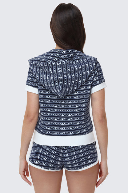 A woman faces away, wearing a sporty navy blue and white Logo Stripe Short Sleeve Zip Hoodie with matching shorts, both featuring horizontal Juicy logo stripes.