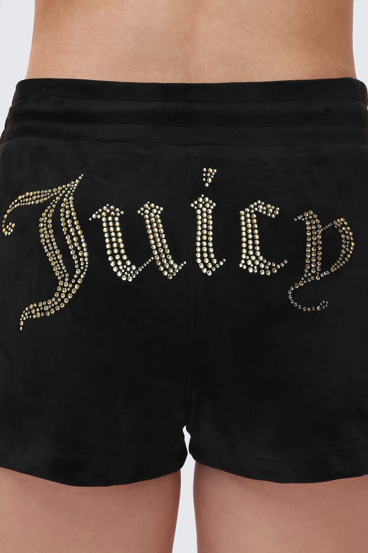A close-up of a person wearing the Big Bling Velour Shorts, featuring a comfy drawstring waist and a rhinestone Juicy logo across the back.