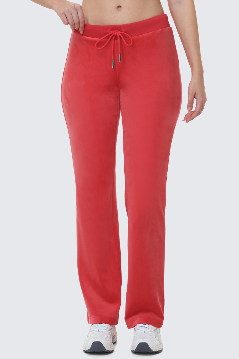 Wearing OG Big Bling Velour Track Pants in bright red with white sneakers, only the lower half is visible against a plain light background—serving major Y2K vibes.