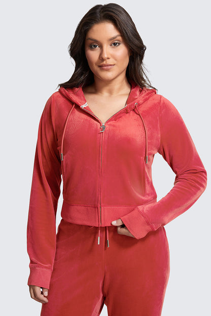 A woman models the Plus-Size OG Big Bling Velour Hoodie and matching pants in red, standing confidently with one hand on her hip against a light gray background.