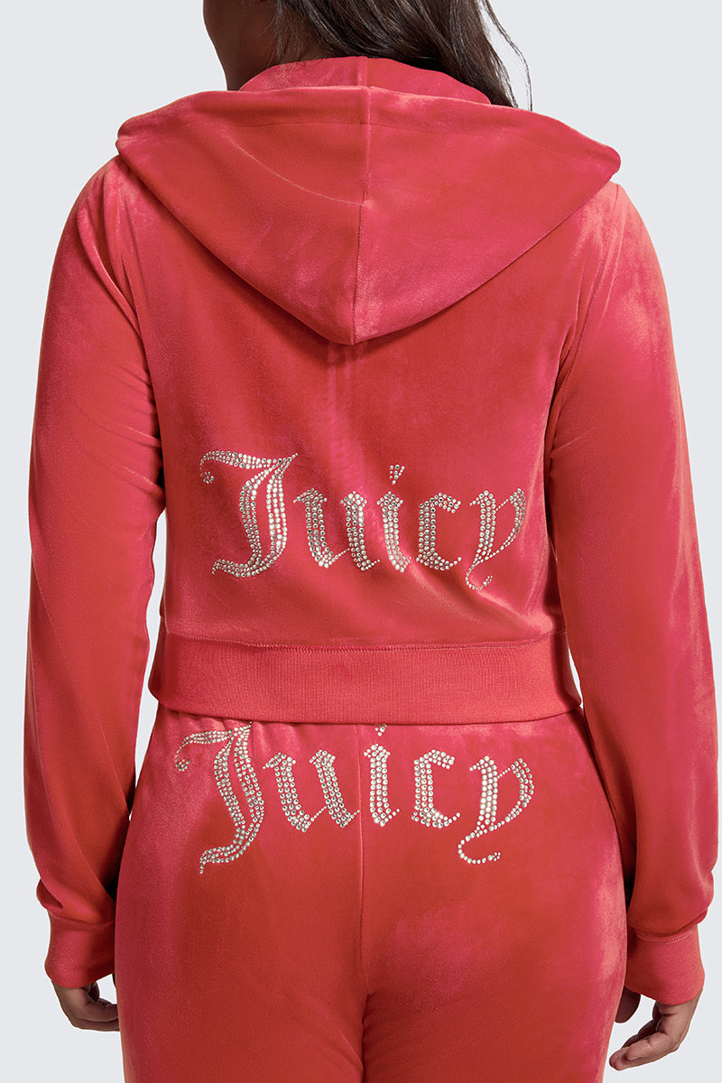 A person is seen from behind wearing the Plus-Size OG Big Bling Velour Hoodie, a pink velour tracksuit with Juicy rhinestone embellishments decorating the back of the jacket and pants.
