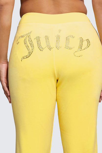 A close-up of the back of a person wearing Plus-Size OG Big Bling Velour Track Pants in yellow, featuring a sparkling rhinestone Juicy embellishment across the seat, inspired by Y2K style.