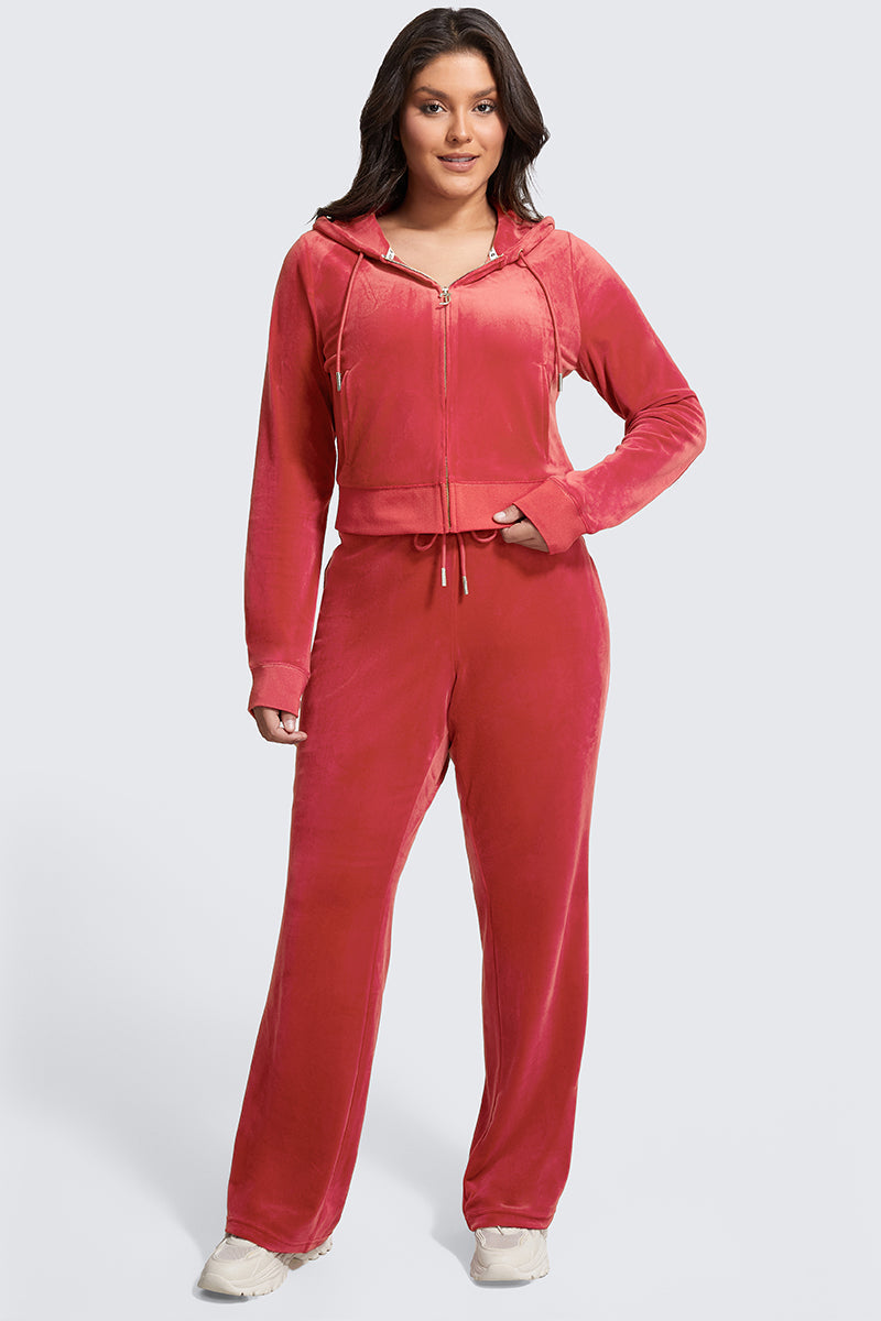 A woman faces forward in Y2K style, wearing Plus-Size OG Big Bling Velour Track Pants with a matching pink zip-up hoodie and white sneakers, set against a plain light gray background.