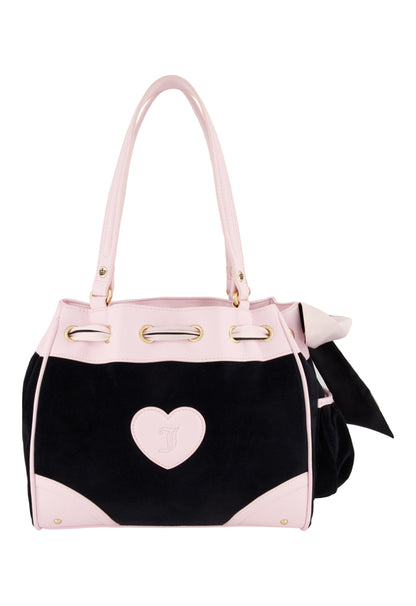 The Royal Bloom Daydreamer Tote Bag features a black body, light pink handles and trim, a heart-shaped front detail, gold hardware, and a chic black bow accent on the side.