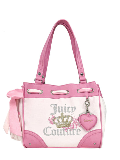 The Royal Bloom Daydreamer Tote Bag by Juicy Couture features pink and white design, double handles, crown logo, silver glitter lettering, a pink side bow, and a heart-shaped keychain—ideal for a glamorous tote collection.