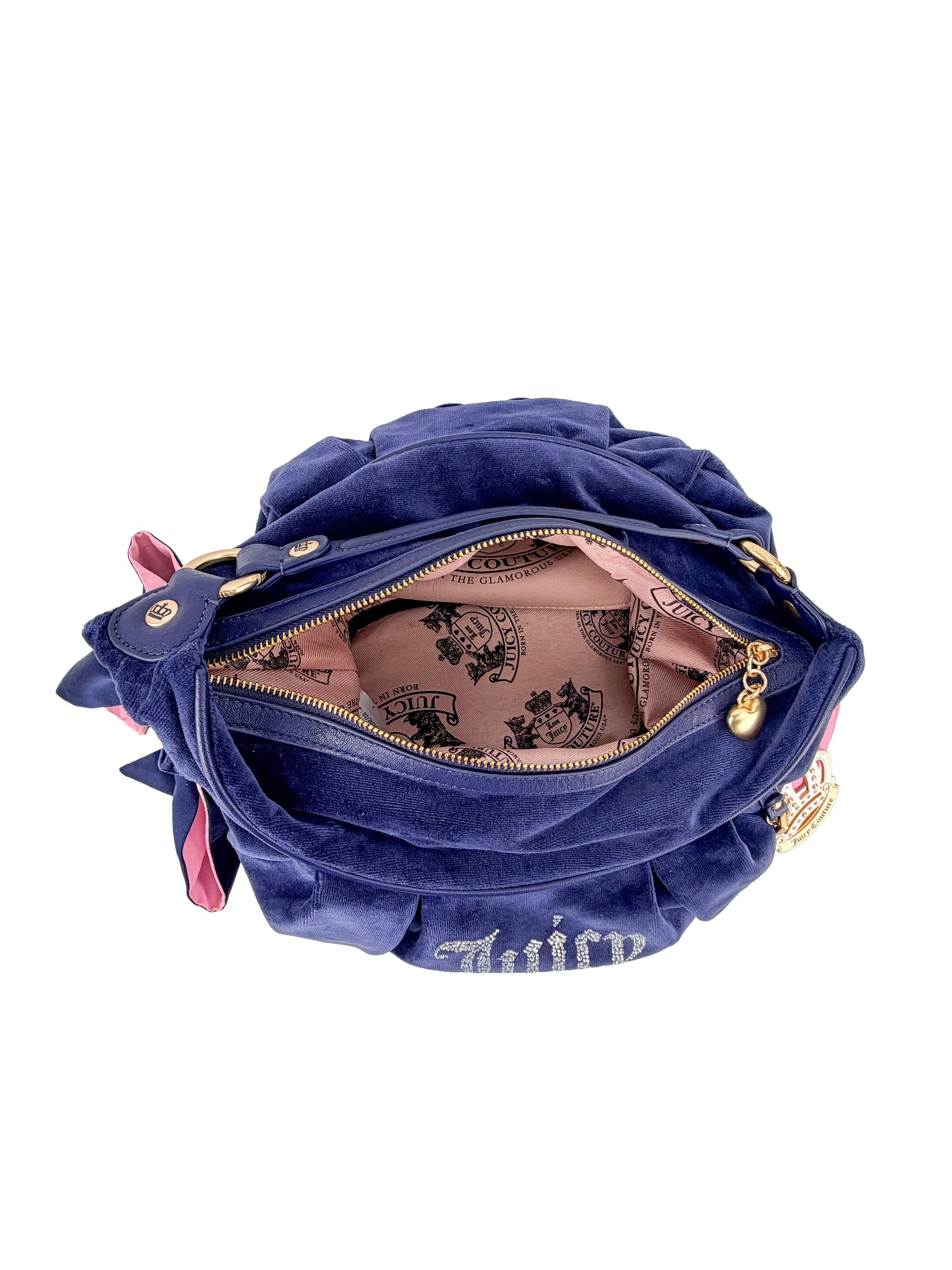 The Royal Bloom Hobo Bag is a blue velvet Juicy Couture handbag with a pink interior, gold hardware, an open zipper showing the patterned lining, and a crown logo inside.