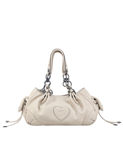 The cream-colored Vintage Vibes Satchel Bag features silver chain handles, drawstring sides, and a stitched heart logo on the front—perfect for adding Juicy throwback glamour to any look.