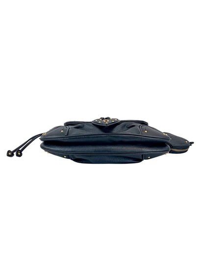 The Vintage Vibes Hobo Bag in black leather is shown from the side lying flat, featuring gold-tone hardware, a front flap with decorative detailing, and a zippered compartment.