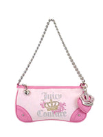 The Royal Bloom Shoulder Bag by Juicy Couture is a small pink and white bag featuring a sleek silhouette, silver chain strap, heart zipper pull, pink crown charm, gold crown and floral design, plus Juicy Couture text on the front.