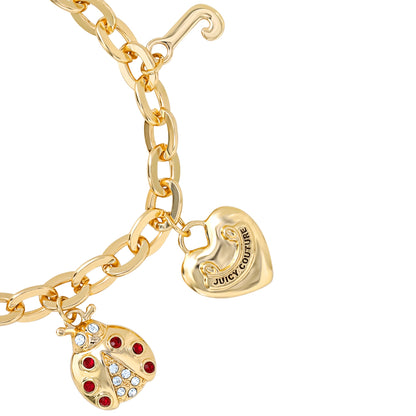 The Pearl & Icon Charm Bracelet features an adjustable gold-tone chain with a jeweled red and clear ladybug charm and a gold heart engraved with Juicy Couture.