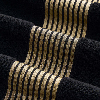 A close-up of textured fabric with black and gold stripes, showcasing raised and flat sections for a wavy 3D effect like the premium weave found in the Melissa Bath Towel Set.