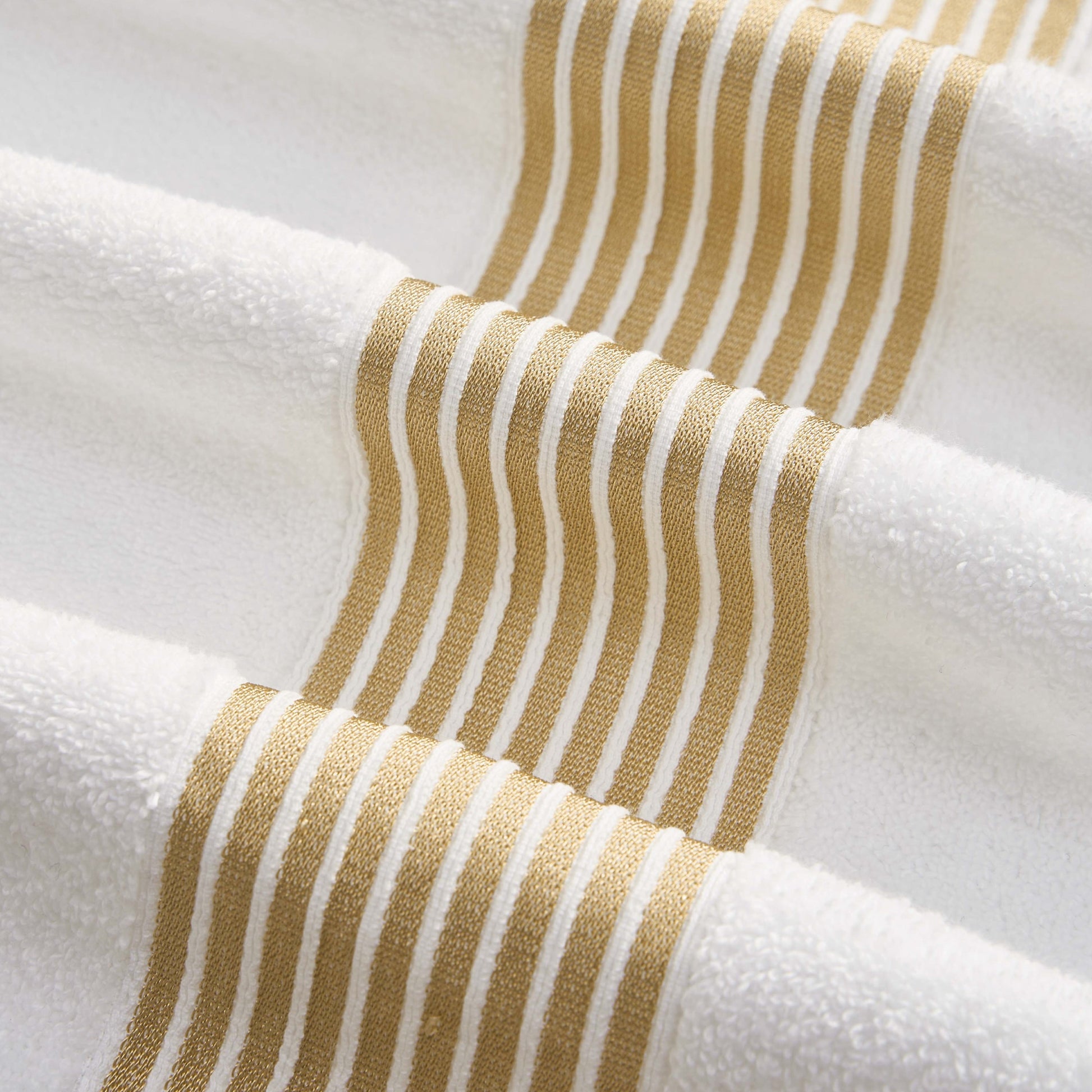 Close-up of the Melissa Bath Towel Set—soft, plush 100% cotton towels accented with horizontal gold wavy stripes for an elegant, visually appealing design.