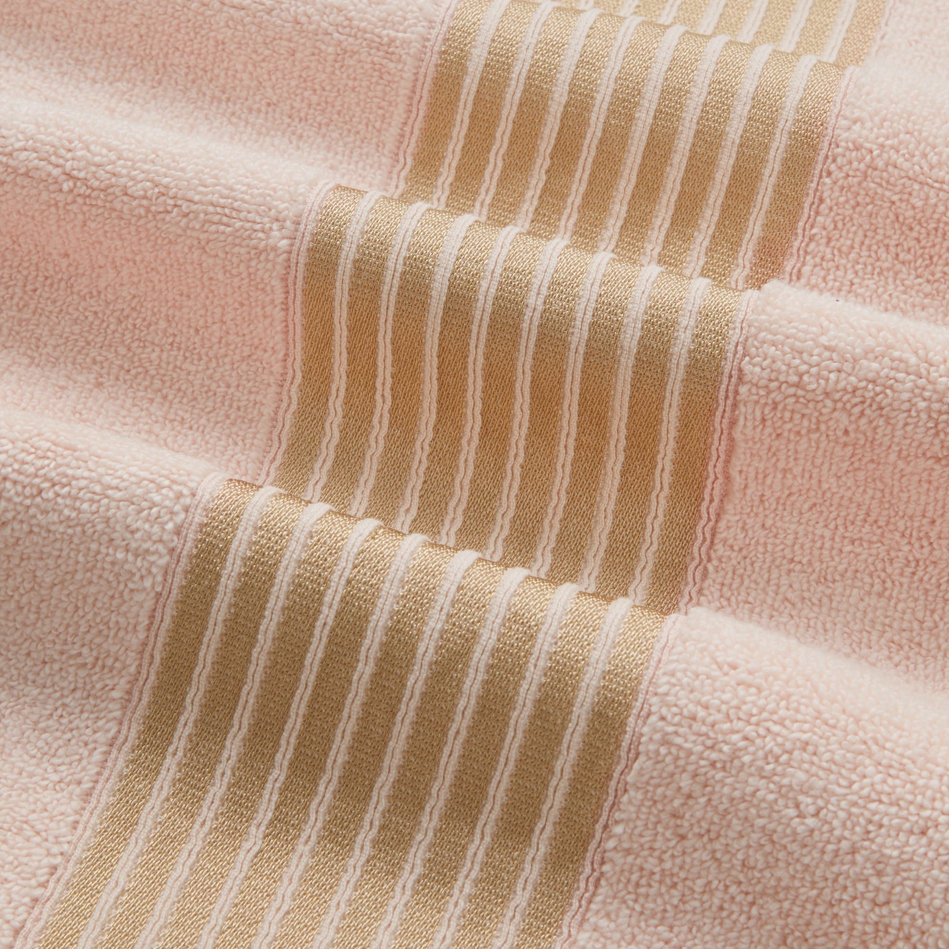 A close-up of the Melissa Bath Towel Set, showcasing soft 100% cotton towels with wide peach and narrow beige stripes, featuring raised ribbed lines on the beige bands for added texture and comfort.