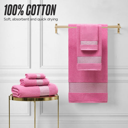 A set of pink Melissa Bath Towel Set with striped accents is displayed—some folded on a round gold table, others hanging on a wall rack. Text reads: 100% cotton, soft, absorbent, and quick drying.