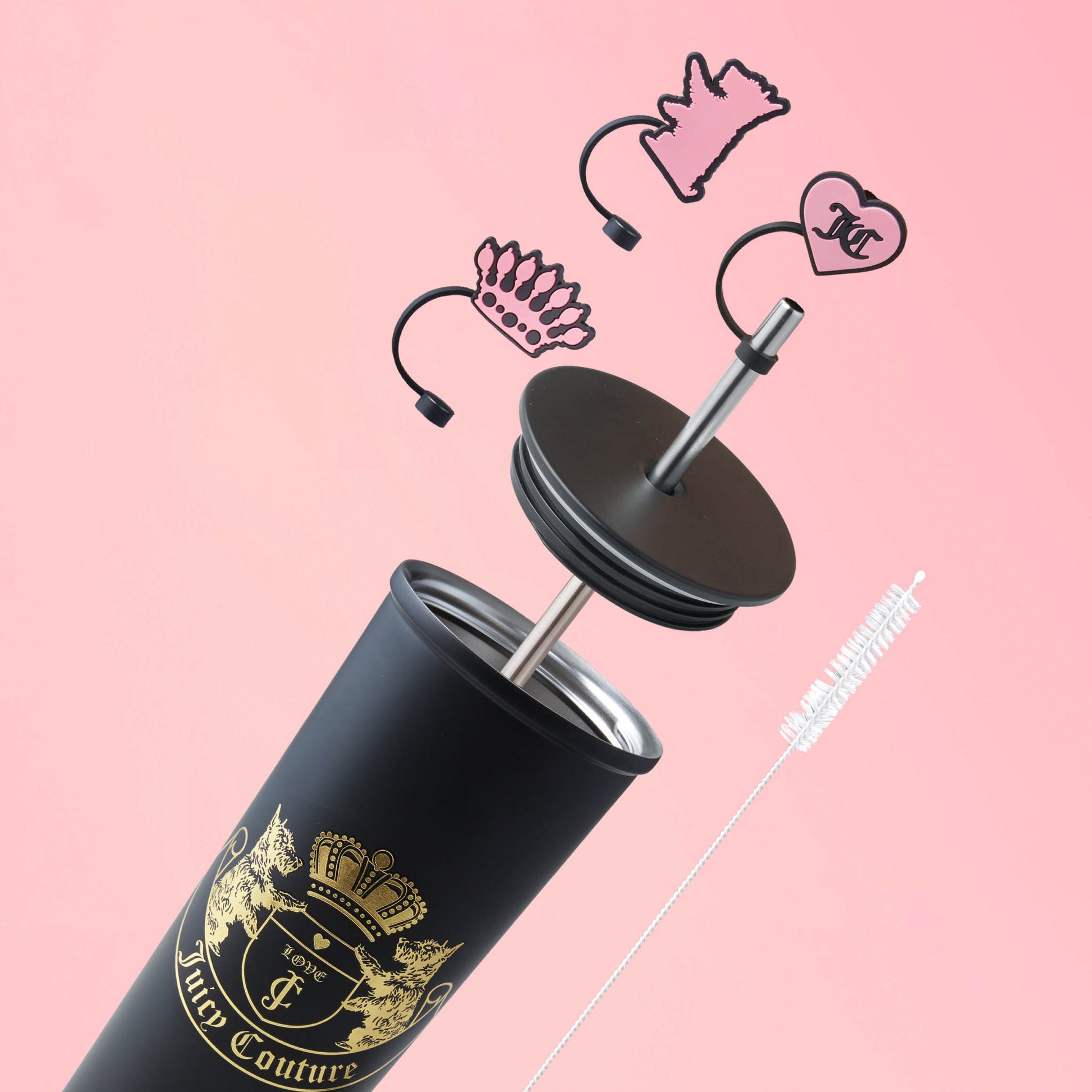 The Couture Hydration Stainless Steel Tumbler Cup 6-Piece Set features a black tumbler with gold branding, lid, straw, and straw toppers displayed on a pink background—a stylish gift set for any occasion.