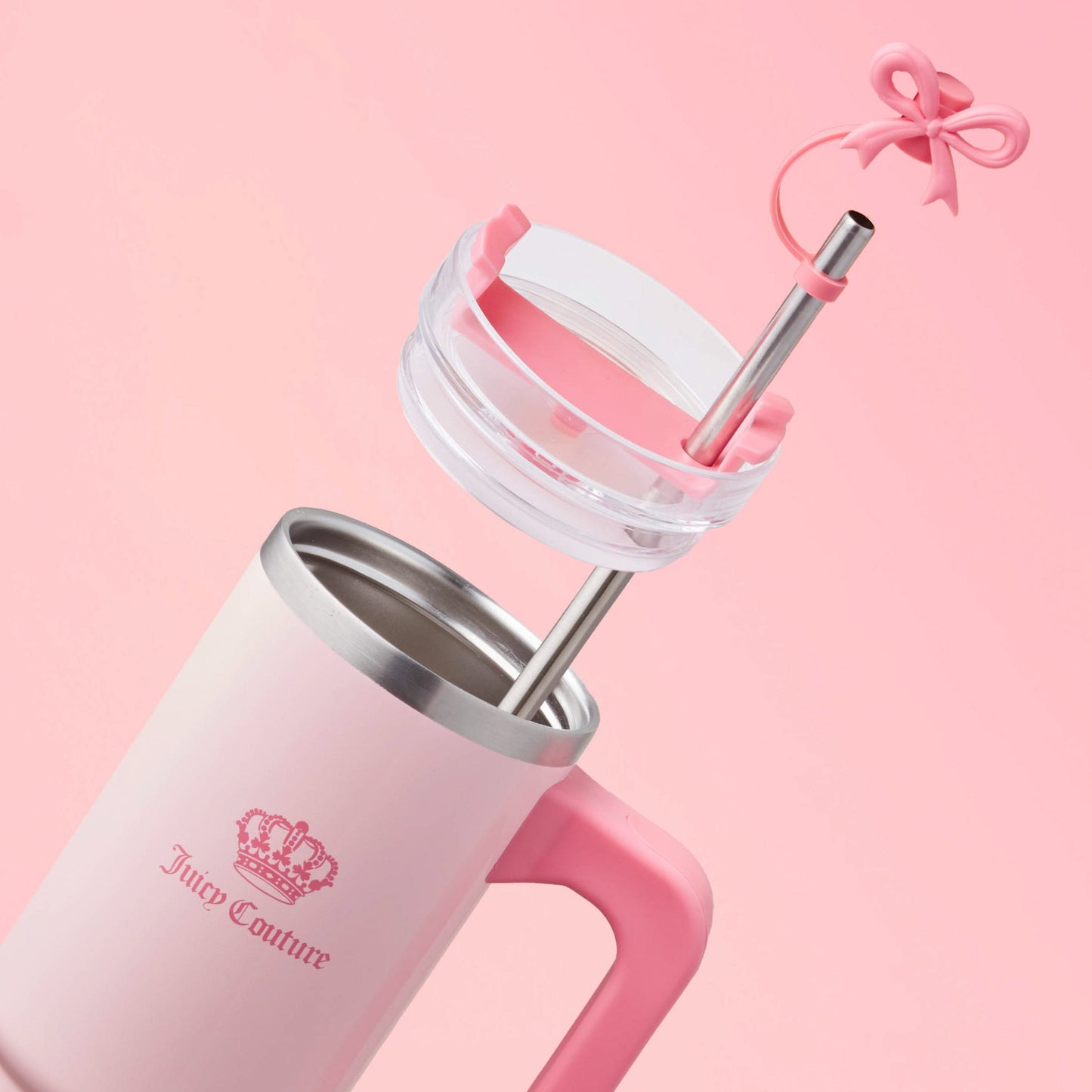 The Jetsetter Hydration Stainless Steel Tumbler with Neoprene Crossbody Pouch features pink and white hues, a stainless steel straw, a pink lid, and a bow-shaped topper, styled on a soft pink background.