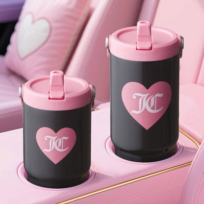 The Flip Flow Hydration Stainless Steel Tumbler Cup 2-Pack features black tumblers with pink lids and heart designs, nestled in pink holders with heart cushions—an ideal mommy and me gift for stylish outings.