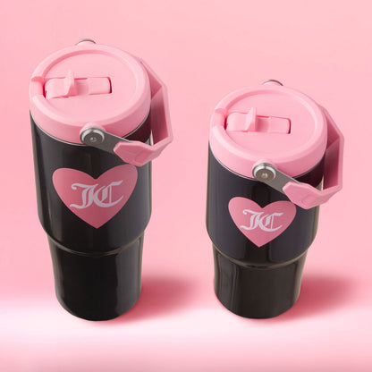 The Flip Flow Hydration Stainless Steel Tumbler Cup 2-Pack is shown in black with pink lids, handles, and heart graphics featuring white “KC” letters, set against a pink background—perfect as a mommy and me gift.