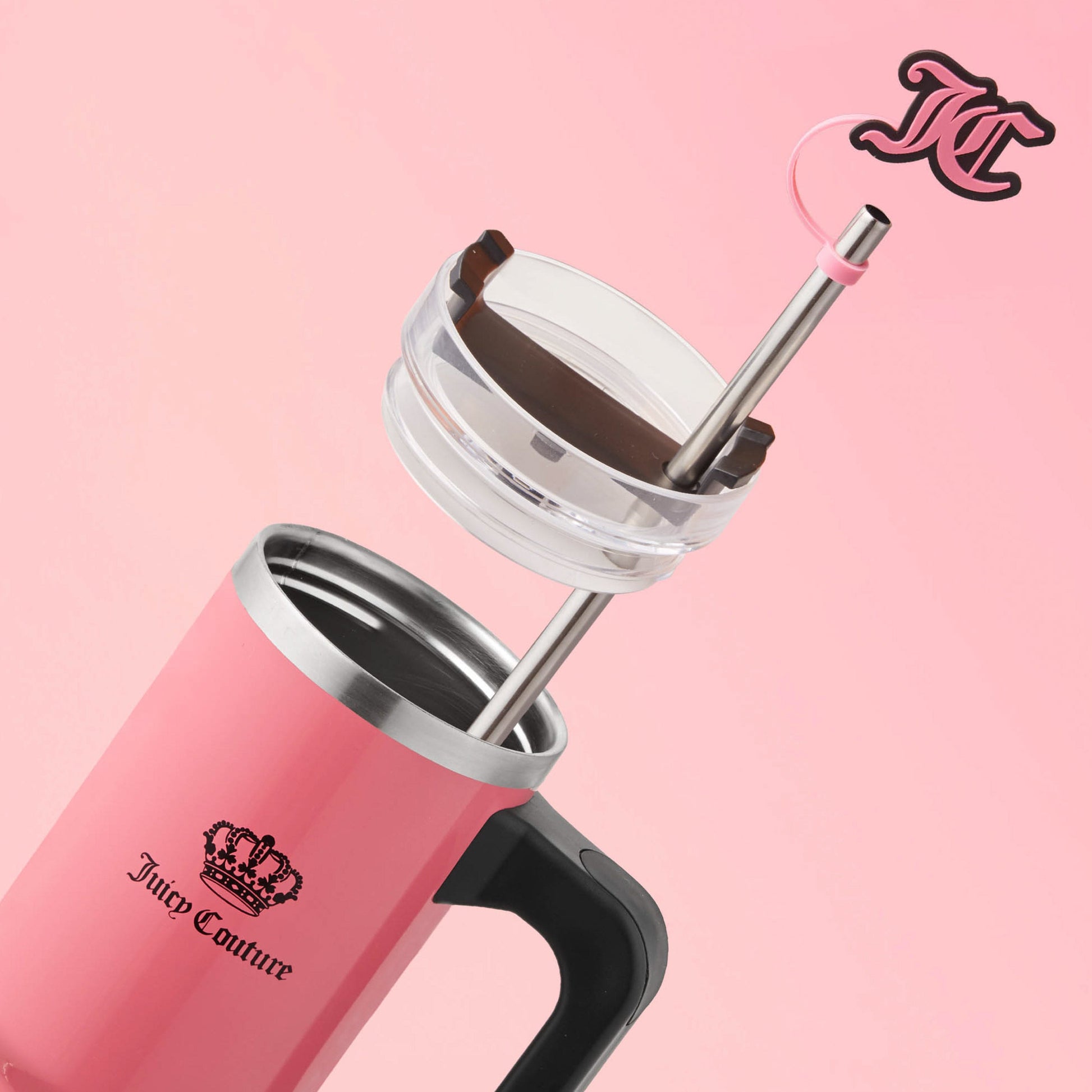 The Jetsetter Hydration Stainless Steel Tumbler with Neoprene Crossbody Pouch, shown in pink with a stainless steel straw and clear lid, features a black Juicy Couture logo against a pink background.