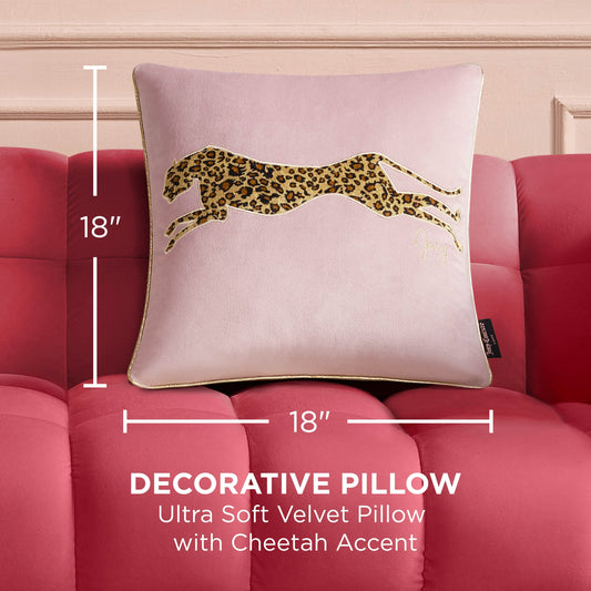The square, pale pink Velvet Cheetah Pillow features an embroidered leaping cheetah design and sits on a pink tufted sofa, adding a chic 18x18-inch accent to your space.