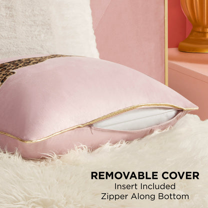 A close-up of the Velvet Cheetah Pillow shows its gold bottom zipper partially open to reveal the white insert. The removable cover rests on a fluffy surface, with a gold lamp and pink wall behind. Insert is included.