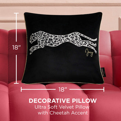 A Velvet Cheetah Square Pillow, featuring a white cheetah design and gold signature on black velvet (18x18 inches), rests on a pink tufted sofa. Text reads: "Ultra soft decorative pillow with cheetah accent.